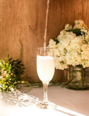 Gözlüklü gül kırmızısı şarap. Arka planda çiçekler olan bir şişe gül şarabı. Prosecco.