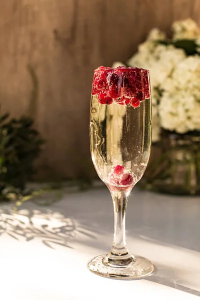 Vin mousseux en verre avec des baies de groseille rouge — Photo