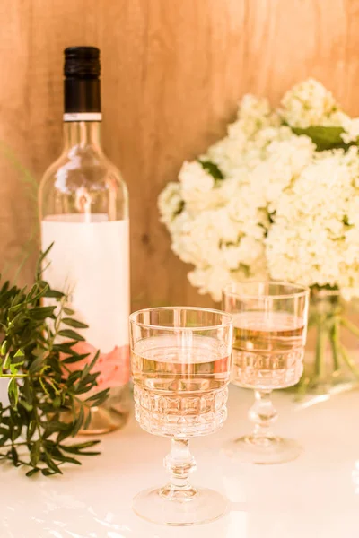 Rose wine in glasses. Rose wine on golden bottles background with flowers and fruits