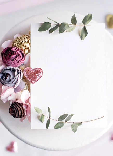 Background with copy space blank on white table with glitter heart, eucalyptus branch, flowers and leafs. White paper top view, flat lay, minimal style. Moke up card. — Stock Photo, Image