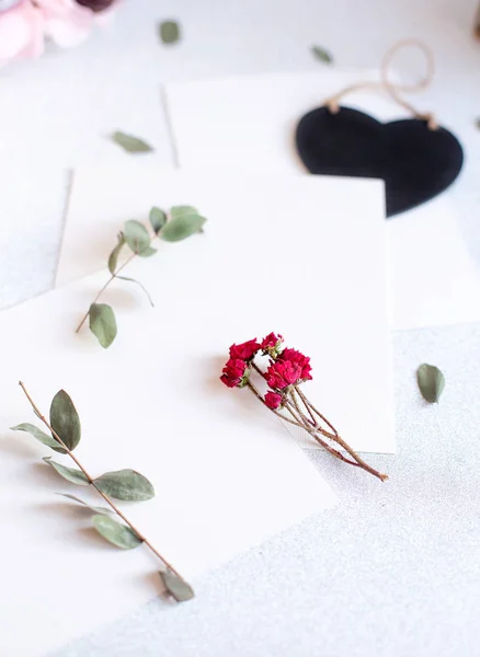 Background with copy space blank on table with black heart, eucalyptus branch, roses flowers and leafs. White paper top view, flat lay, minimal style. Moke up card. — 스톡 사진