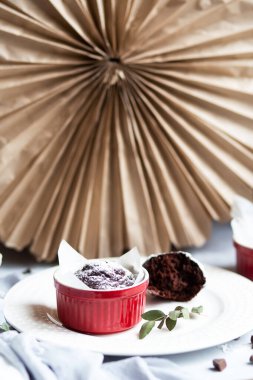 Kırmızı bardakta çikolatalı kek. Gri ve beyaz arka planda kahverengi kekleri olan küçük seramik ramekin..