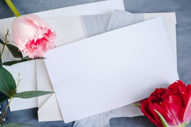 Boş kağıt kopyalama alanı. Çiçeklerle çerçevelenmiş. İpek kurdele. Gri arka plan. Basit bir buket. Tebrik kartı.