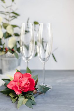 Composition with glass for champagne. Flowers and hearts on grey concrete background.
