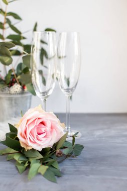 Composition with glass for champagne. Flowers and hearts on grey concrete background.