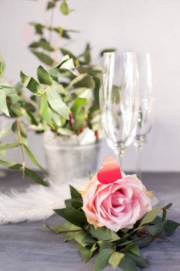 Composition with glass for champagne. Flowers and hearts on grey concrete background.