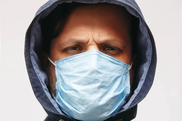 Coronavirus 'tan korumak için maskeli bir adam. Corona virüsü salgını. Tıbbi maskeli genç adam izole edildi. Kapüşonlu, tıbbi maskeli biri. COVID 19