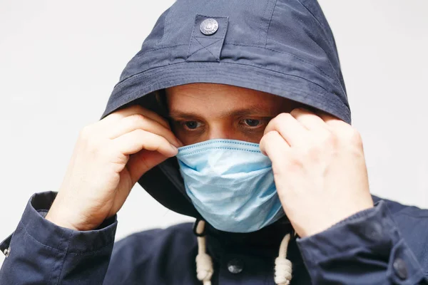 Coronavirus 'tan korumak için maskeli bir adam. Corona virüsü salgını. Tıbbi maskeli genç adam izole edildi. Kapüşonlu, tıbbi maskeli biri. COVID 19