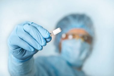Doktorun el ele tutuşan aşısını kapatın. Tıbbi ekipman. COVID 19 Coronavirus enfeksiyonunu korumak için maske, gözlük ve giysi de dahil olmak üzere kişisel koruyucu ekipman giyen bir doktor..