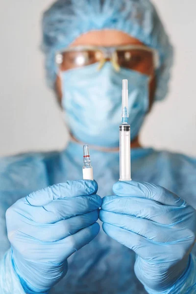 Doktorun el ele tutuşan aşısını kapatın. Tıbbi ekipman. COVID 19 Coronavirus enfeksiyonunu korumak için maske, gözlük ve giysi de dahil olmak üzere kişisel koruyucu ekipman giyen bir doktor..