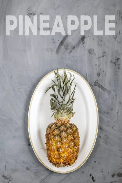 Gri Beton Arkaplanda Olgun Ananaslı Beyaz Tabak. Kelime Ananas