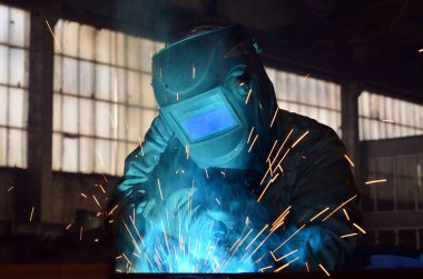 Fabrikada çalışan kaynakçılar metal üretiyorlar.