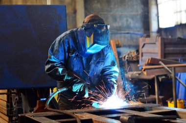 Fabrikada çalışan kaynakçılar metal üretiyorlar.