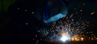 Fabrikada çalışan kaynakçılar metal üretiyorlar.