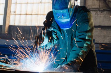 Fabrikada çalışan kaynakçılar metal üretiyorlar.
