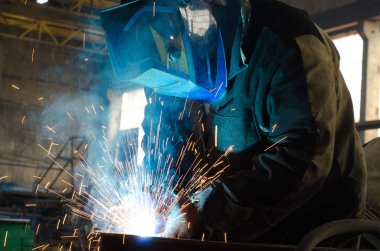 Fabrikada çalışan kaynakçılar metal üretiyorlar.