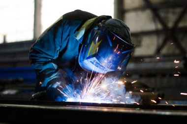 Fabrikada çalışan kaynakçılar metal üretiyorlar.