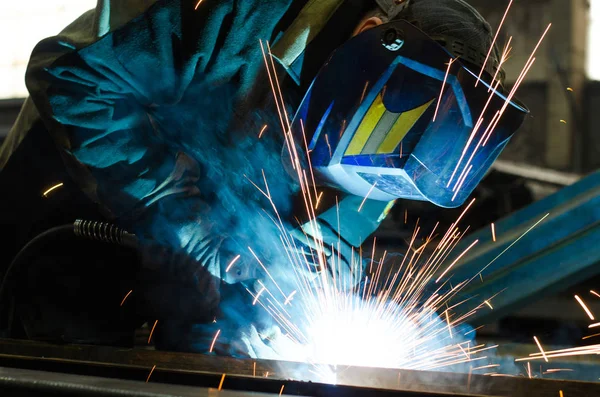 Fabrikada çalışan kaynakçılar metal üretiyorlar.