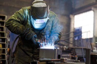 Fabrikada çalışan kaynakçılar metal üretiyorlar.