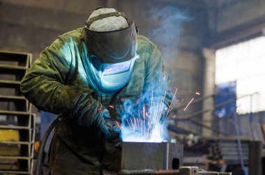 Fabrikada çalışan kaynakçılar metal üretiyorlar.