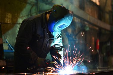 Fabrikada çalışan kaynakçılar metal üretiyorlar.