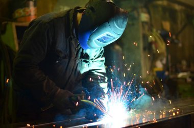Fabrikada çalışan kaynakçılar metal üretiyorlar.