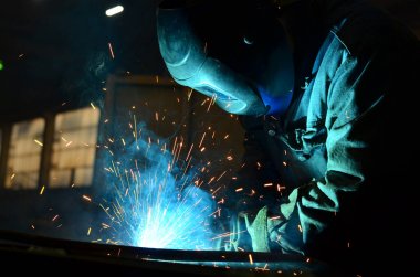 Fabrikada çalışan kaynakçılar metal üretiyorlar.