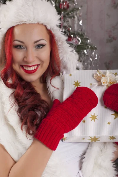 美丽微笑的女人模型与毛皮帽子展示圣诞礼物 — 图库照片