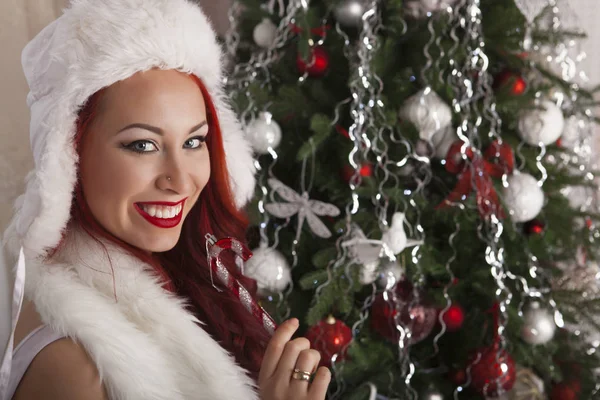 Рождественская девушка Санта, улыбающаяся модель рядом сосна с подарками. Элегантная леди в белом платье в новогоднем интерьере — стоковое фото
