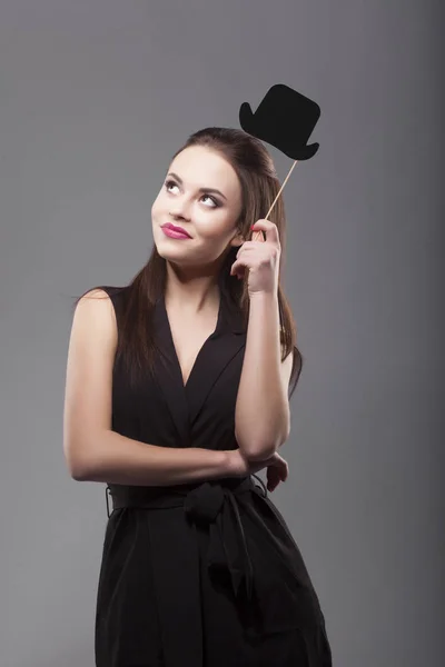 Chica sosteniendo sombrero cilindro de papel divertido en palo, aislado, fondo gris. Joven sonrisa alegre de la mujer de moda — Foto de Stock