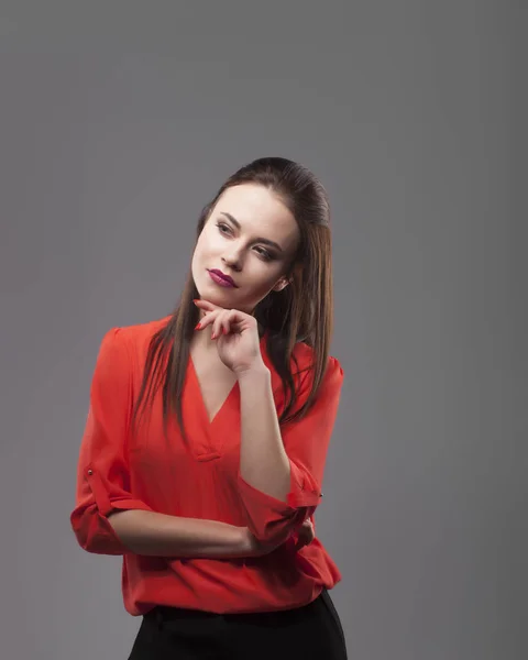 Chica de camisa roja, fondo gris. Joven y alegre morena de moda. Pensando —  Fotos de Stock