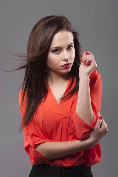 Chica de camisa roja, fondo gris. Joven alegre de la moda morena mujer con movimiento de pelo — Foto de Stock