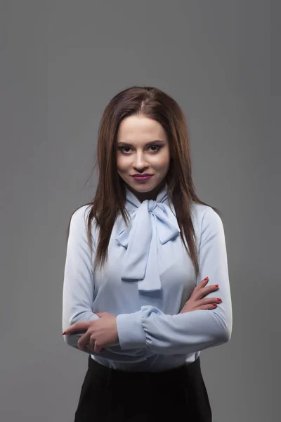 Fille en chemise bleue, fond gris. Joyeuse jeune femme brune souriante à la mode avec du rouge à lèvres rose et des mains croisées. Portrait — Photo