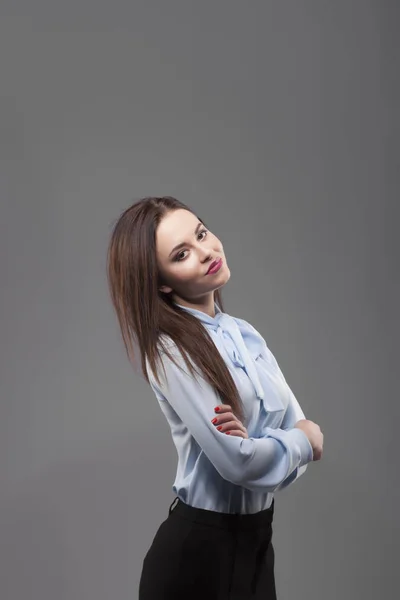 Fille en chemise bleue, fond gris. Joyeuse jeune femme brune souriante à la mode avec du rouge à lèvres rose et des mains croisées. Portrait — Photo