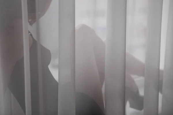 Silueta en forma perfecta de esconderse en tul elegante seductora joven con lencería que se divierte feliz relajándose sobre la luz de la ventana —  Fotos de Stock