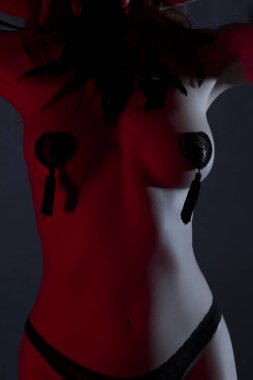 Seksi ince kadın, burlesque dansçı, siyah maske ve tüyler tanınmaz striptizci. Kırmızı aydınlatma ile koyu arka plan