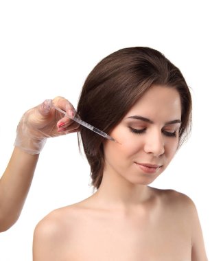 Çekici genç kadın beyaz arka plan üzerinde izole kapalı gözlerle kozmetik enjeksiyon alır. Doktorlar ellerini yüzüne bir enjeksiyon yapma.