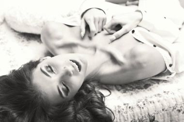 Açık ağızlı nefes. Bağsız kıl ve ince beden giyen erkek gömlek yalan evde yatak odası, kapalı photoshoot, siyah ve beyaz atış ile çekici ve rahat baştan çıkarıcı genç kadın