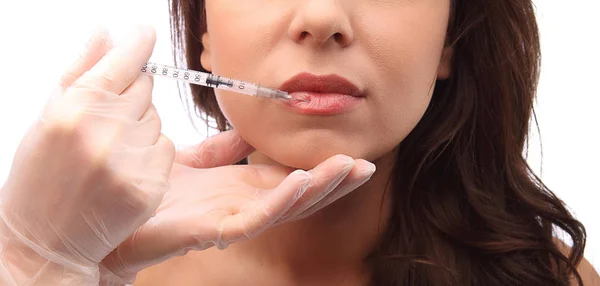 Aantrekkelijke jonge vrouw krijgt cosmetische injecties in lippen, geïsoleerd op witte achtergrond in de studio close-up shot gezicht — Stockfoto