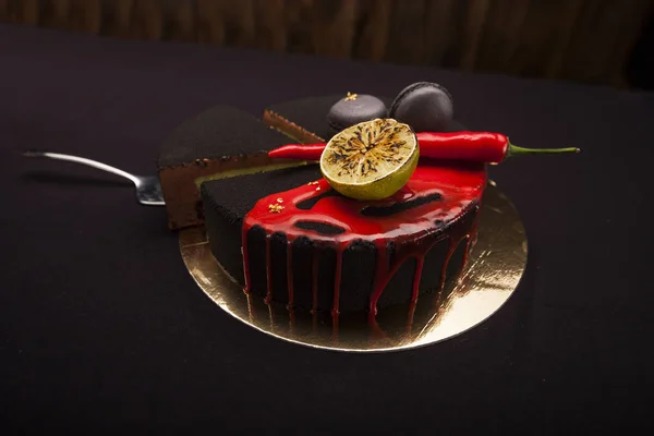 Bolo coberto com veludo preto. limão, pimenta e macaroons, esmalte vermelho em cima. Um bolo moderno com uma peça de corte no fundo preto — Fotografia de Stock