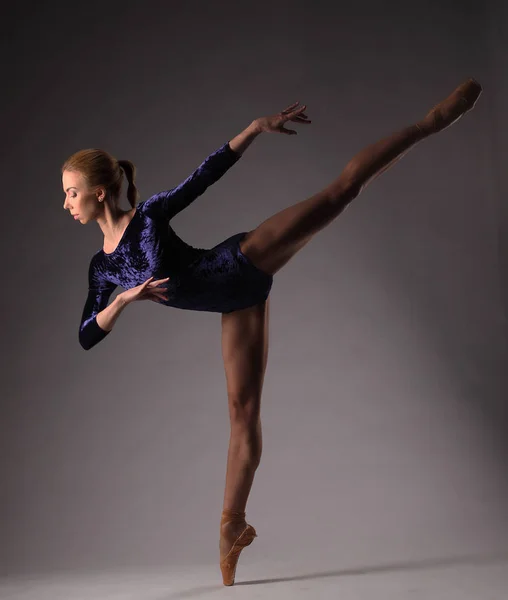 Ballerina in blue outfit posing on toes, studio shot. on one leg — Stock Photo, Image