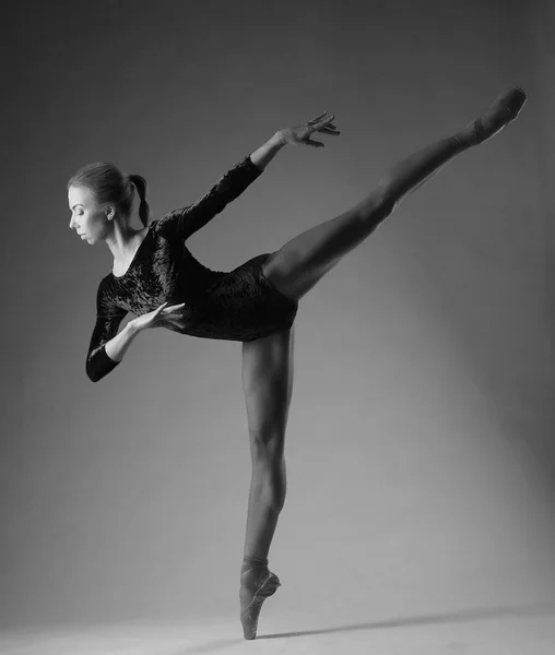Балерина в черном наряде позирует на пальцах ног, студийный снимок. на одной ноге, черно-белое изображение — стоковое фото