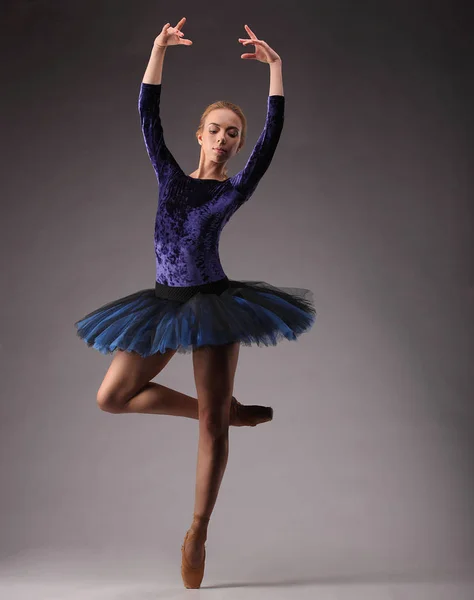 Jovem e incrivelmente bela bailarina em roupa azul está posando e dançando em estúdio. arte ballet clássico. numa perna — Fotografia de Stock