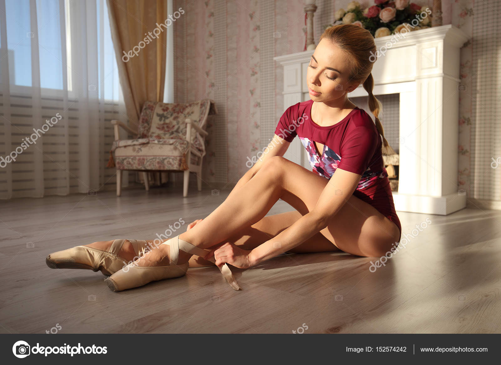 Beautiful legs of young ballerina who puts on pointe shoes sitting