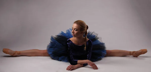 Bailarina em roupa azul show dividido no chão do estúdio — Fotografia de Stock