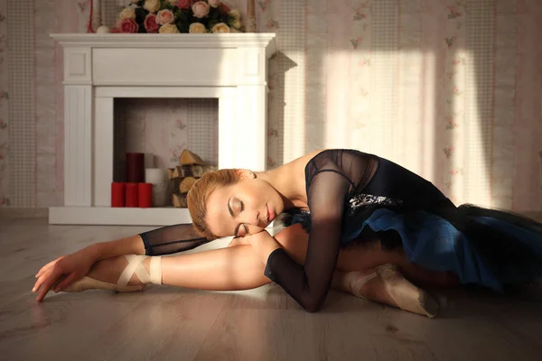 Porträt einer professionellen Balletttänzerin, die mit geschlossenen Augen im Sonnenlicht auf dem Holzboden sitzt. Ballerina beim Ausruhen. Ballettkonzept. — Stockfoto