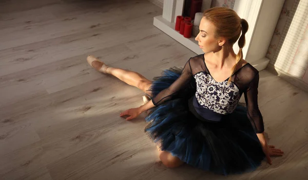 Balletdanseres zittend op de houten vloer. Vrouwelijke ballerina een rust. Ballet concept. — Stockfoto