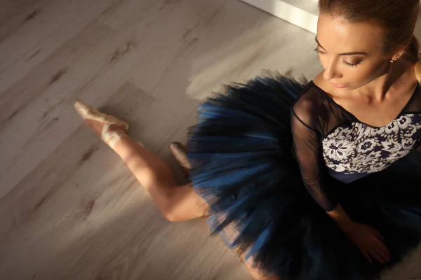 Widok z góry z profesjonalną baletnicą w niebieski tutu i obuwie pointe siedzieć na podłodze. Tło — Zdjęcie stockowe