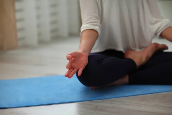 Joga w domu. Atrakcyjna kobieta nie do poznania, siedząc w pozycji lotosu na podłodze, ręce i nogi strzał zbliżenie — Zdjęcie stockowe