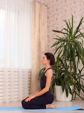 Yoga poz evde oturan kadın. Kadın meditasyon mat oturma odasında egzersiz onun dairenin yapıyor spor giyim.